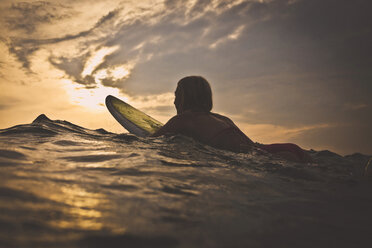 Frau surft im Meer gegen den Himmel bei Sonnenuntergang - CAVF26766