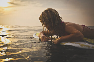 Frau auf Surfbrett im Meer liegend gegen Himmel - CAVF26770
