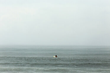 Mann mit Surfbrett im Meer gegen den Himmel bei nebligem Wetter - CAVF26786