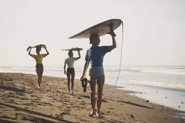 Freunde tragen Surfbrett beim Spaziergang am Strand gegen den Himmel - CAVF26789