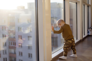 Junge in voller Länge am Fenster stehend, zu Hause - CAVF26810