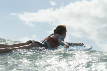 Side view of woman surfing on sea against cloudy sky - CAVF26824