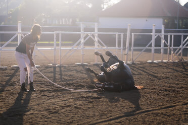 Frau in voller Länge, die ein Pferd auf einer Ranch trainiert - CAVF26829