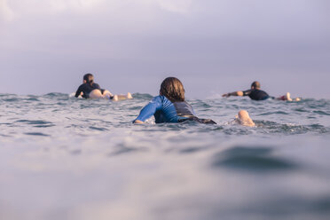 Rear view of friends surfing in sea against sky - CAVF26849