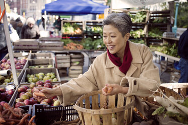 Glückliche reife Frau kauft Gemüse auf dem Bauernmarkt - CAVF26893