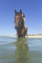 Indonesien, Bali, Frau sitzt auf Pferd, im Wasser - KNTF01104
