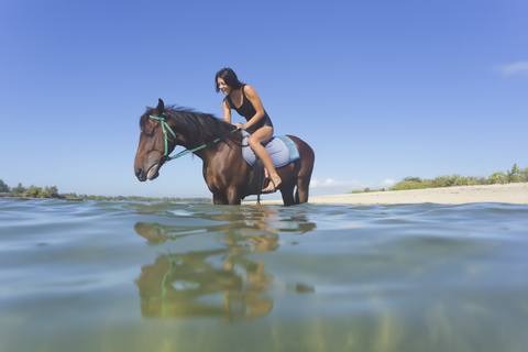 Indonesien, Bali, Frau sitzt auf Pferd, im Wasser, lizenzfreies Stockfoto