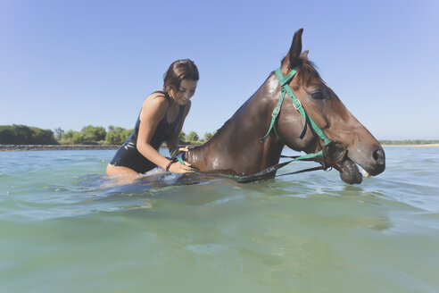 Indonesia, Bali, Woman sitting on horse in water - KNTF01110