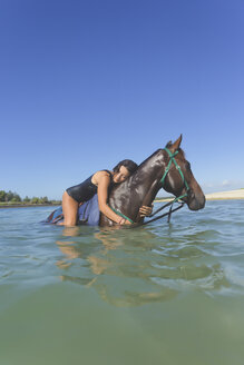 Indonesia, Bali, Woman lying on horse, in water - KNTF01111