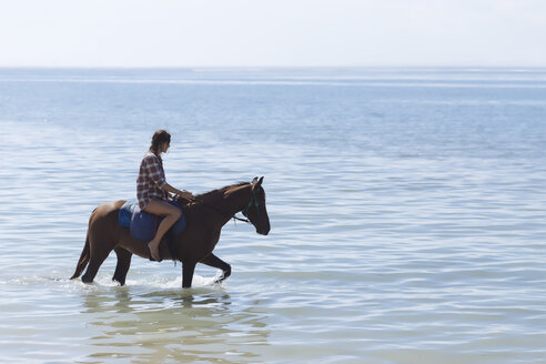 Indonesien, Bali, Frau reitet auf einem Pferd am Strand - KNTF01115