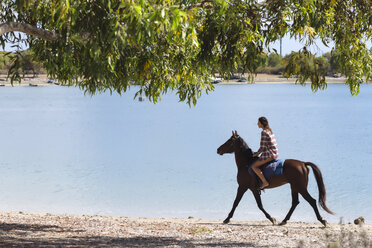 Indonesia, Bali, Woman riding a horse at beach - KNTF01116