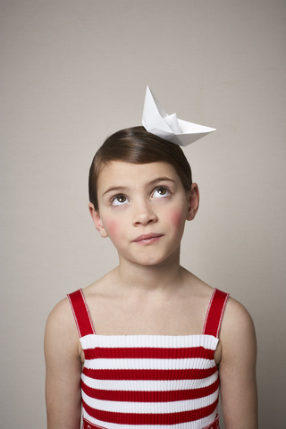 Portrait of little girl with paper boat on her head stock photo