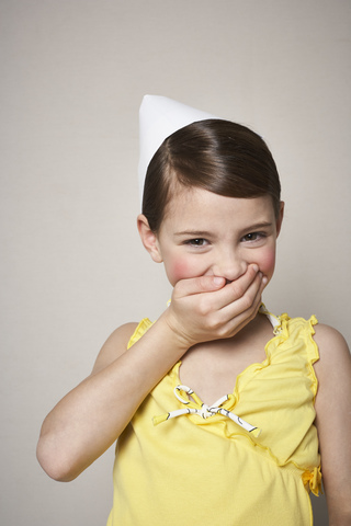 Portrait of laughing little girl wearing paper hat stock photo