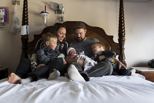 Glückliche Familie auf dem Bett sitzend zu Hause - CAVF26918