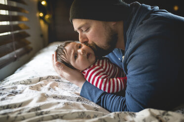 Vater küsst kleines Mädchen, während er zu Hause auf dem Bett liegt - CAVF26923