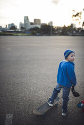 Rückansicht eines Jungen mit Skateboard auf einem Feld - CAVF26928