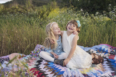 Cheerful sisters sitting on blanket in park - CAVF26943