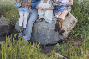 Tiefschnitt von Eltern, die mit ihren Töchtern auf einem Felsen im Park sitzen - CAVF26948