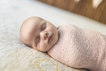 Close-up of baby girl sleeping while wrapped in blanket on bed - CAVF26955