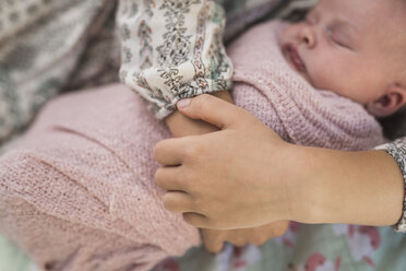 Abgeschnittene Hände einer Schwester, die ein neugeborenes Baby hält - CAVF26965