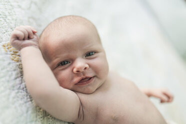 Portrait of shirtless smiling baby girl lying on bed at home - CAVF26991