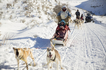 Family dogsledding on snowy field - CAVF27019