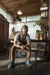 Portrait of confident carpenter sitting on bench in workshop - CAVF27037