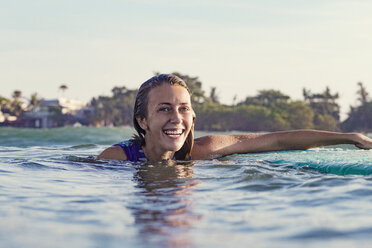 Happy young woman swimming in sea against clear sky - CAVF27108