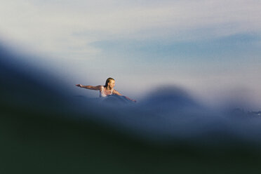 Entfernte Ansicht einer Frau, die im Meer surft, gegen den Himmel - CAVF27109