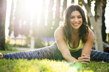 Cheerful woman practicing yoga while exercising in park - CAVF27128