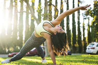 Full length of woman stretching while practicing yoga in park - CAVF27131