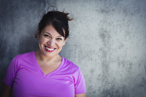 Porträt einer fröhlichen Frau mit rotem Lippenstift an der Wand eines Yogastudios - CAVF27137