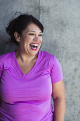 Happy woman looking away while standing against wall in yoga studio - CAVF27138