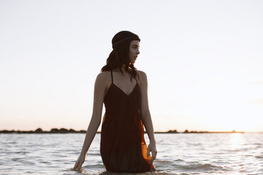 Young woman standing in water against clear sky - CAVF27154