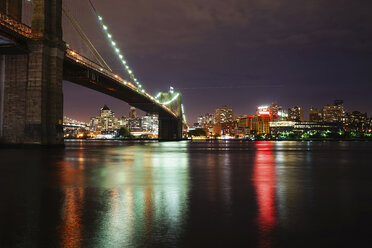 Illuminated Brooklyn Bridge over river against illuminated city - CAVF27216