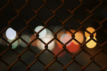 Unscharfe Lichter durch den Zaun bei Nacht gesehen - CAVF27218