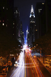 Light trails on city street by illuminated buildings at night - CAVF27222