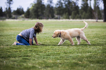 Seitenansicht eines Mädchens, das mit einem Hund auf einem Feld spielt - CAVF27252