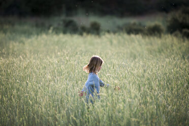 Seitenansicht eines rennenden Mädchens in einem grasbewachsenen Feld - CAVF27257