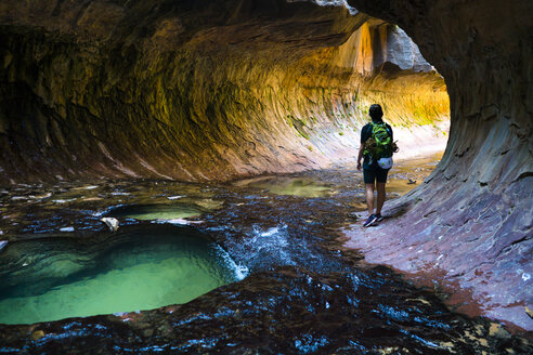 Rear view of hiker walking in cave - CAVF27297