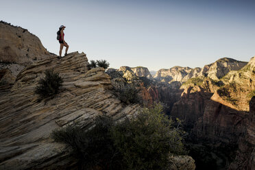 Hiker standing on rock formation and looking at view against clear sky - CAVF27303