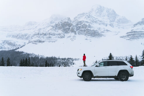 Seitenansicht eines Wanderers, der im Winter mit einem Geländewagen auf einem schneebedeckten Feld steht - CAVF27327