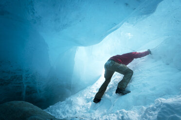 Niedriger Blickwinkel auf einen Wanderer beim Eisklettern in einer Höhle - CAVF27333