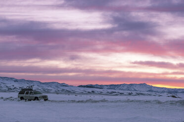 Hohe Winkelansicht eines Geländewagens auf einem verschneiten Feld vor einem dramatischen Himmel - CAVF27379