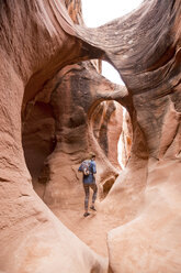 Rear view of woman with backpack hiking in rock formations - CAVF27384