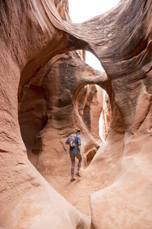 Rear view of woman with backpack hiking in rock formations - CAVF27384