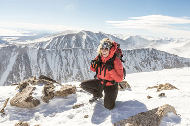 Glückliche Frau kniend auf einem schneebedeckten Berg gegen den Himmel - CAVF27396