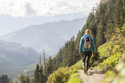 Rear view of female hiker with backpack walking against mountains stock photo