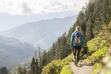 Rückansicht einer Wanderin mit Rucksack, die gegen Berge läuft - CAVF27400