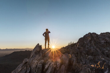 Rückansicht einer Wanderin, die bei Sonnenaufgang auf einer Klippe gegen den klaren Himmel steht - CAVF27408